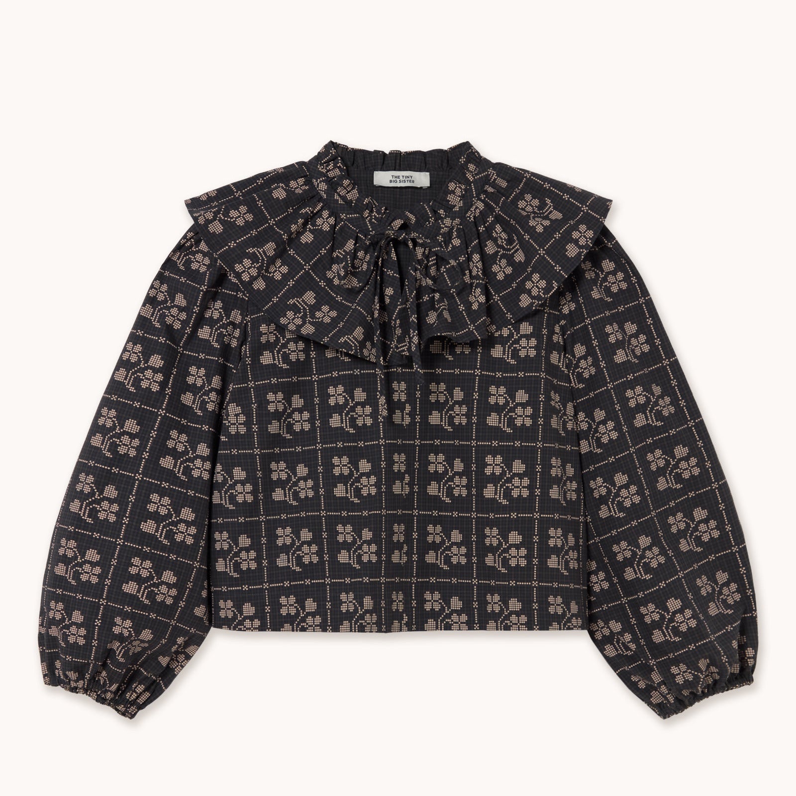 blouse in navy, black and ecru with a ruffled collar on a white background. the label says tiny big sister.