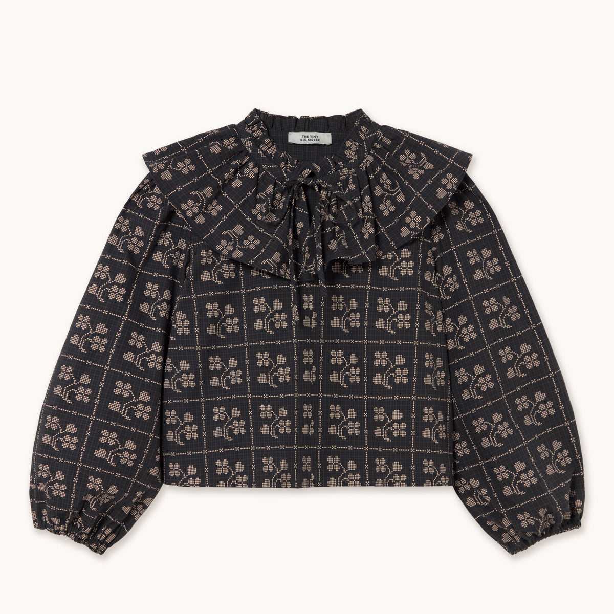 blouse in navy, black and ecru with a ruffled collar on a white background. the label says tiny big sister.