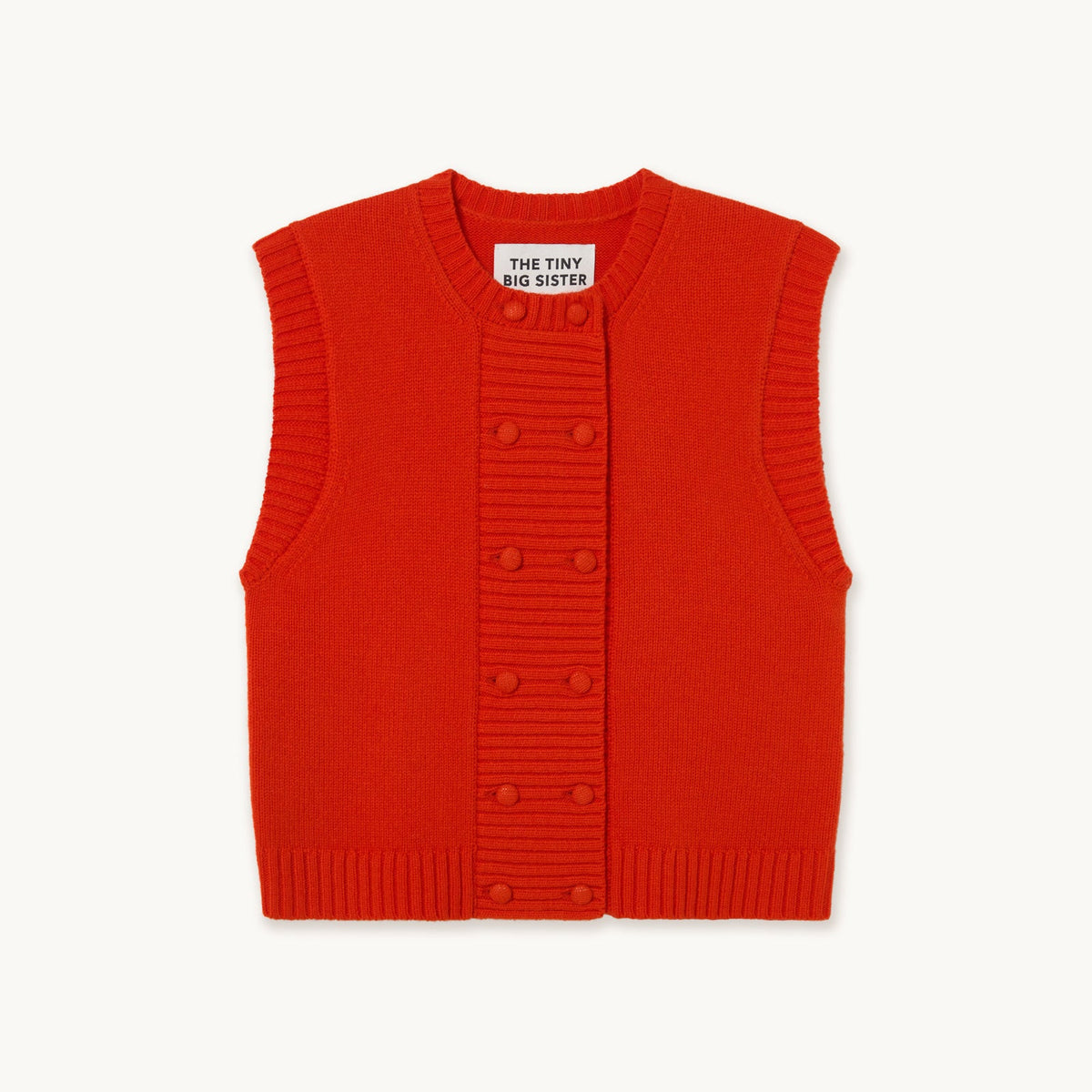 A bright red ribbed knit vest with a button-up front, displayed flat against a light off-white background. The brand label 'THE TINY BIG SISTER' is visible inside the collar.