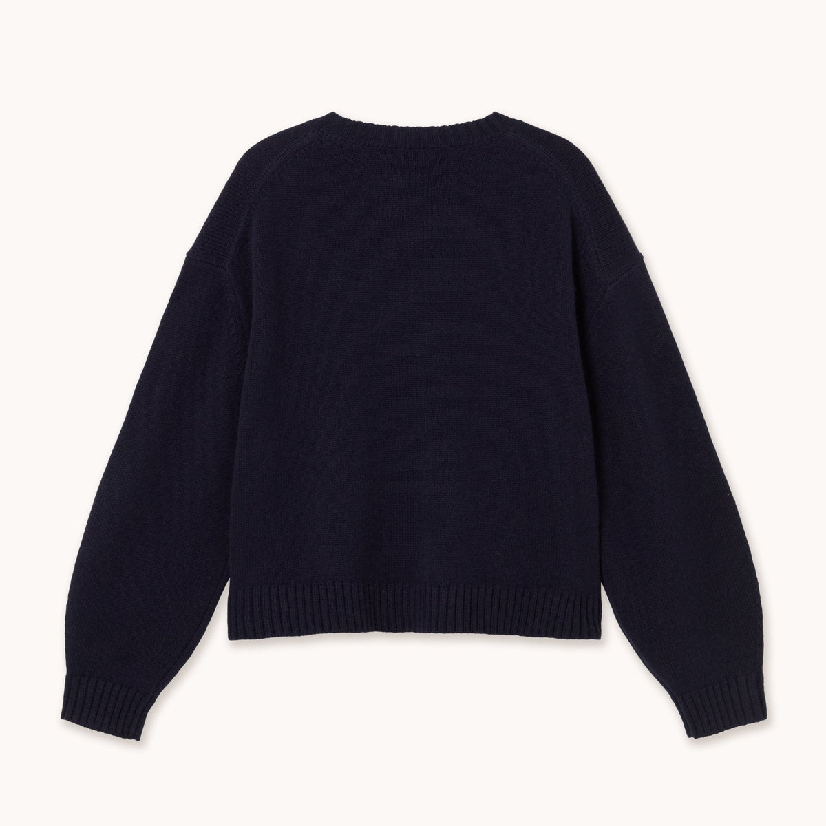 A dark navy blue knit sweater with long sleeves and ribbed cuffs and hem, shown from the back on a light cream background.