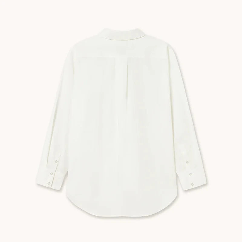 A white long-sleeve blouse shown from the back, featuring a subtle vertical pleat down the center back, buttoned cuffs, and a curved hem, displayed on a clean off-white background.