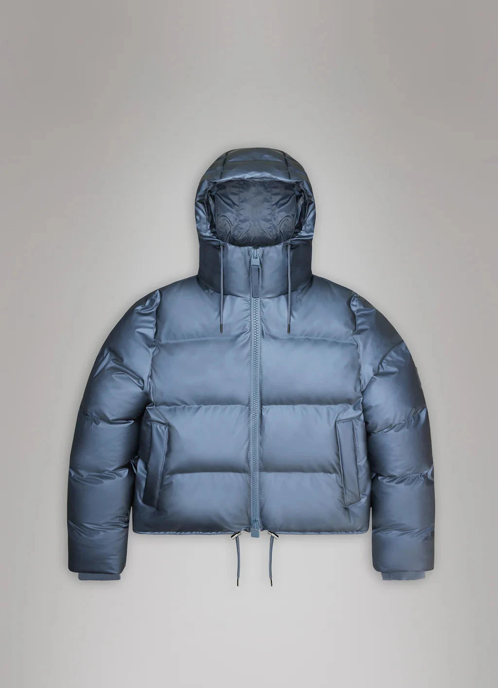 Displayed against a plain grey background, the Alta Short Puffer Jacket from Rains features a blue waterproof design with a hood and front zipper. Perfect for winter, this jacket seamlessly combines style and functionality.