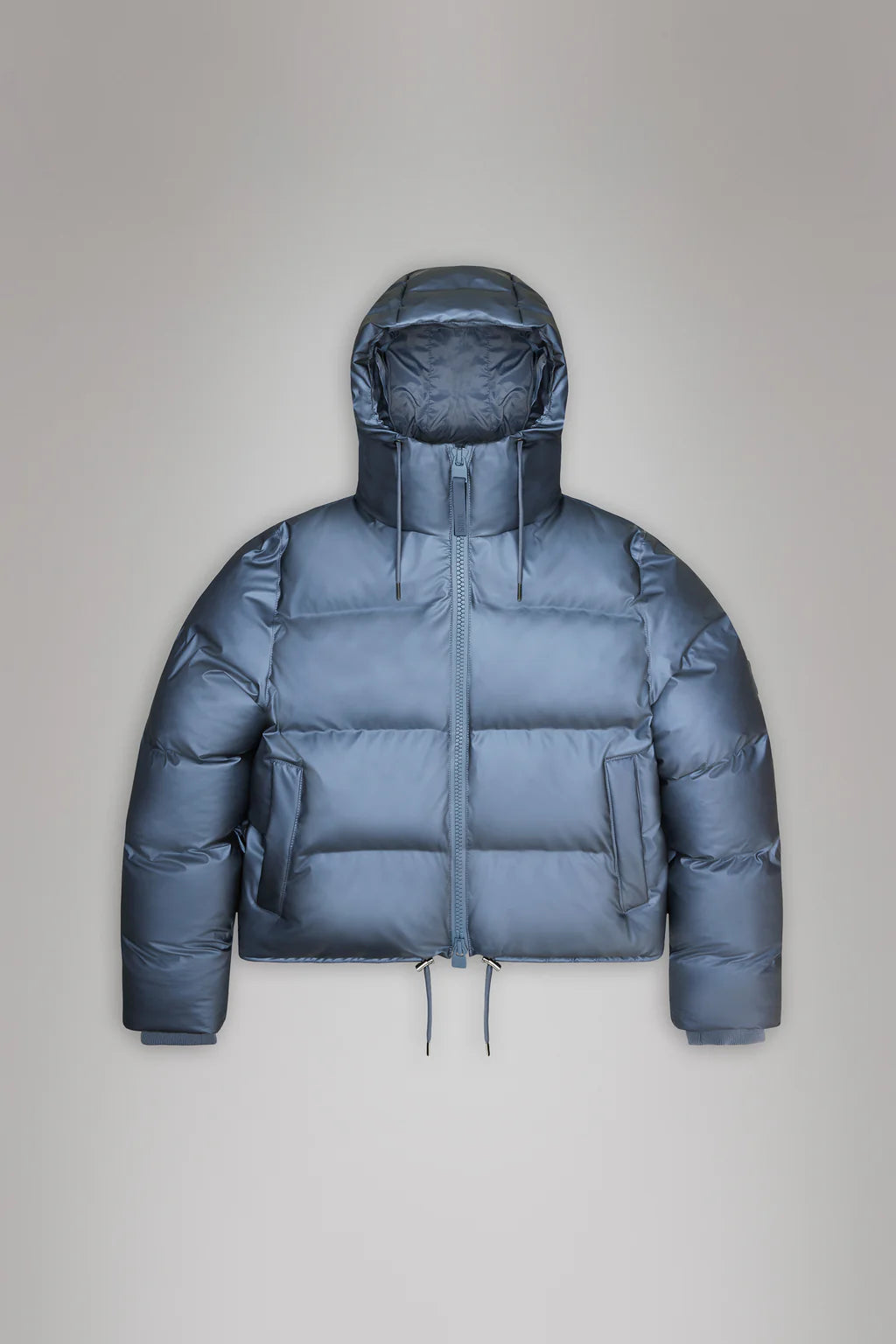 Displayed against a plain grey background, the Alta Short Puffer Jacket from Rains features a blue waterproof design with a hood and front zipper. Perfect for winter, this jacket seamlessly combines style and functionality.