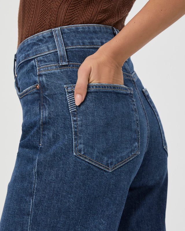 Close-up of a person wearing a brown sweater and vintage-inspired denim, with their right hand placed in the back pocket of their ultra high-waisted Anessa Wide Leg - Alana jeans from Paige.