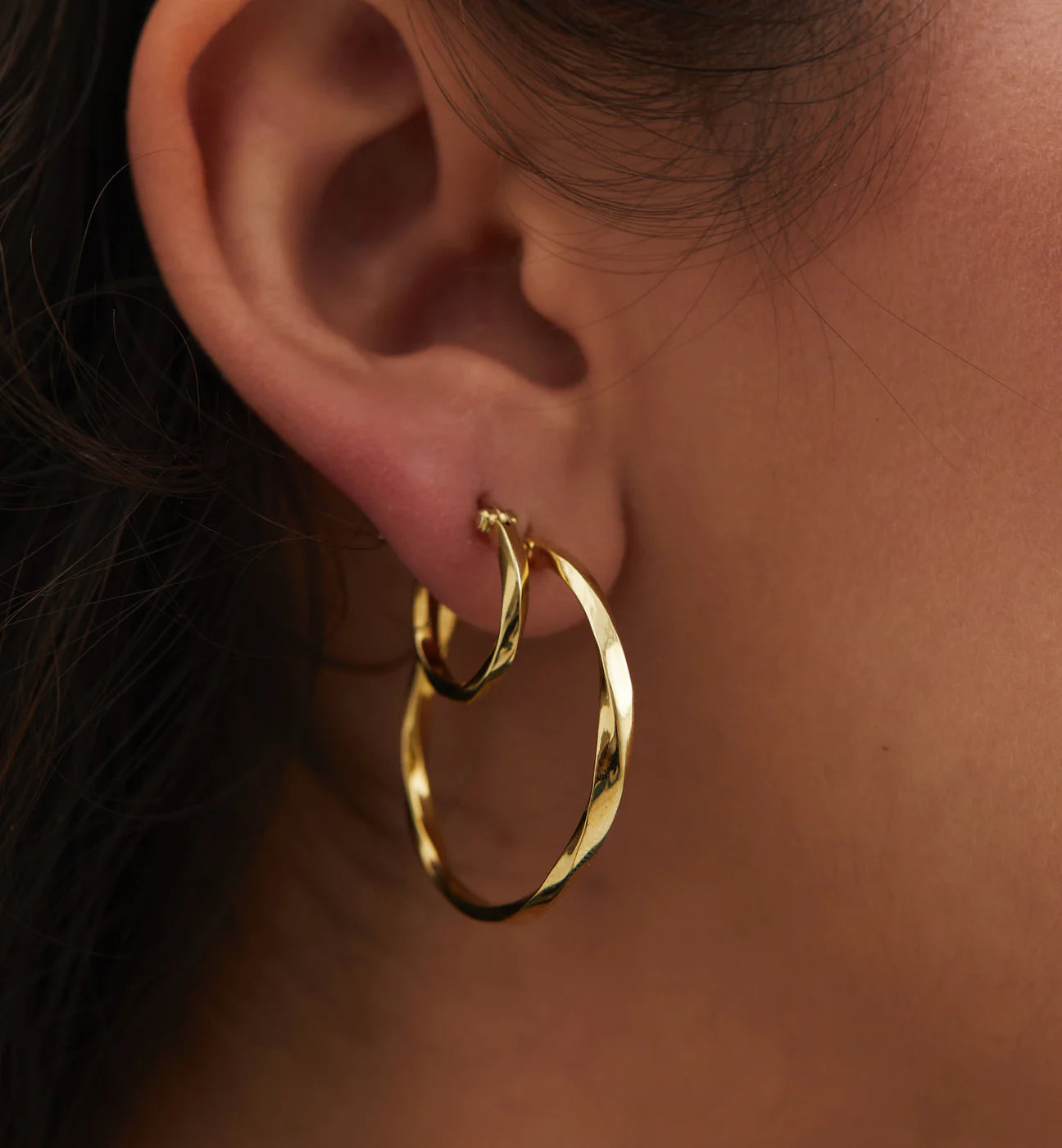 model wears dazzling hoop earrings gold