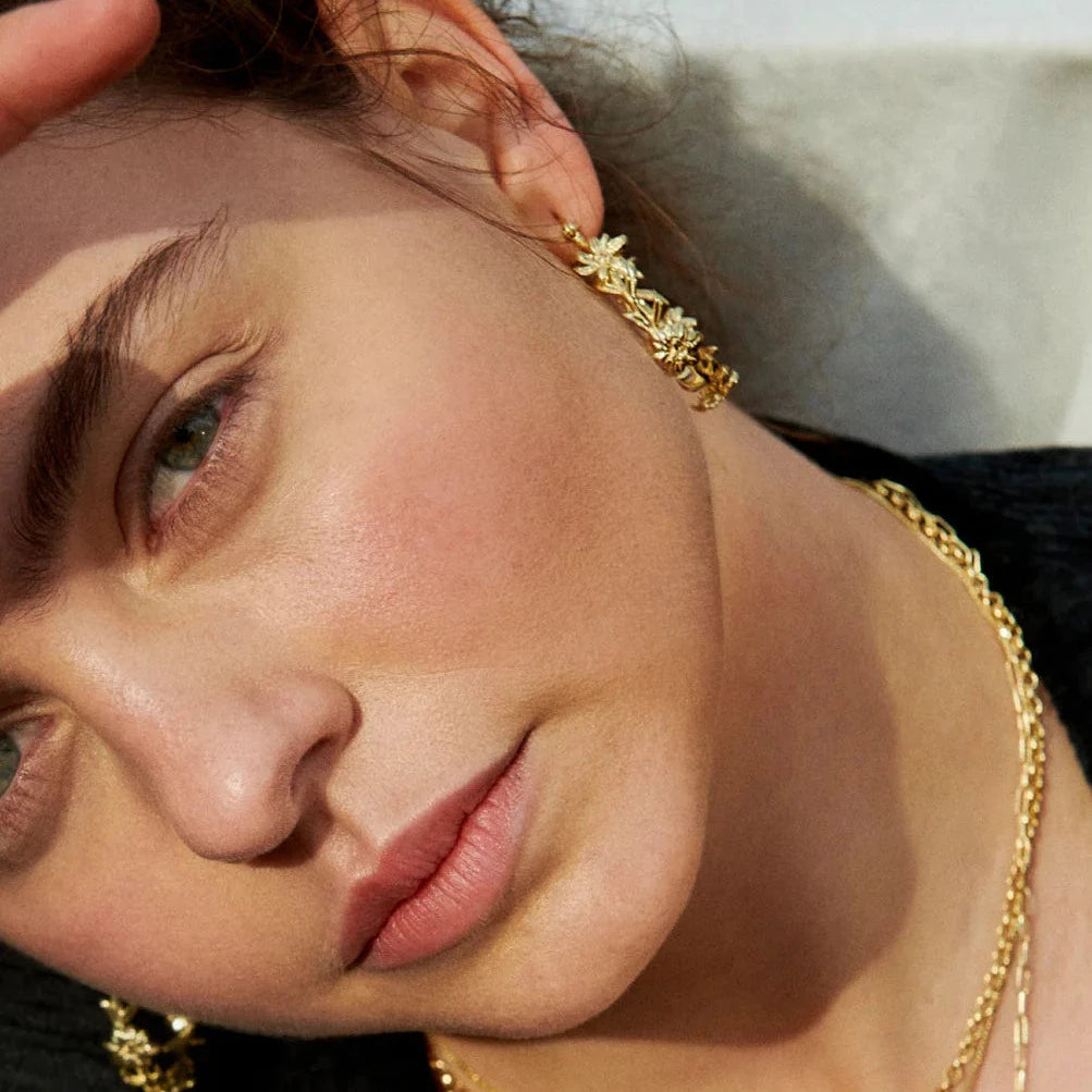 model wearing gold flower design hoops