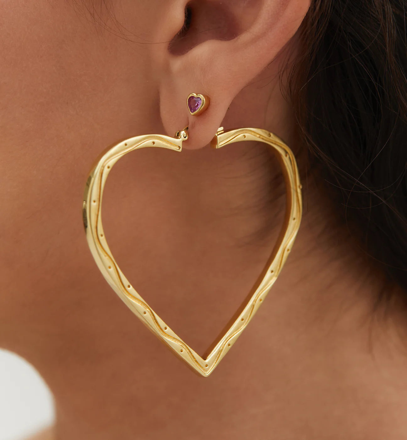 model wearing gold heart shaped hoop earrings
