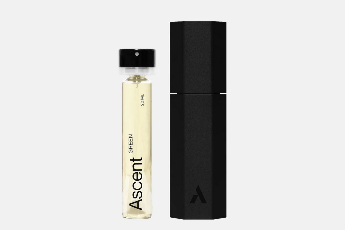 A cylindrical bottle of Ascent Starter Pack - Green perfume next to a black hexagonal protective case.