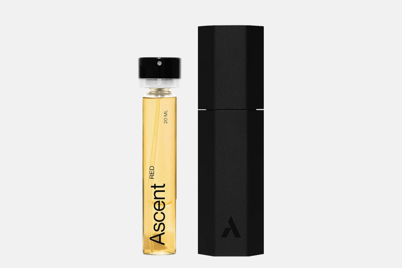 An Ascent Starter Pack - Red glass vial of amber-woody perfume extract next to a tall, black hexagonal container.