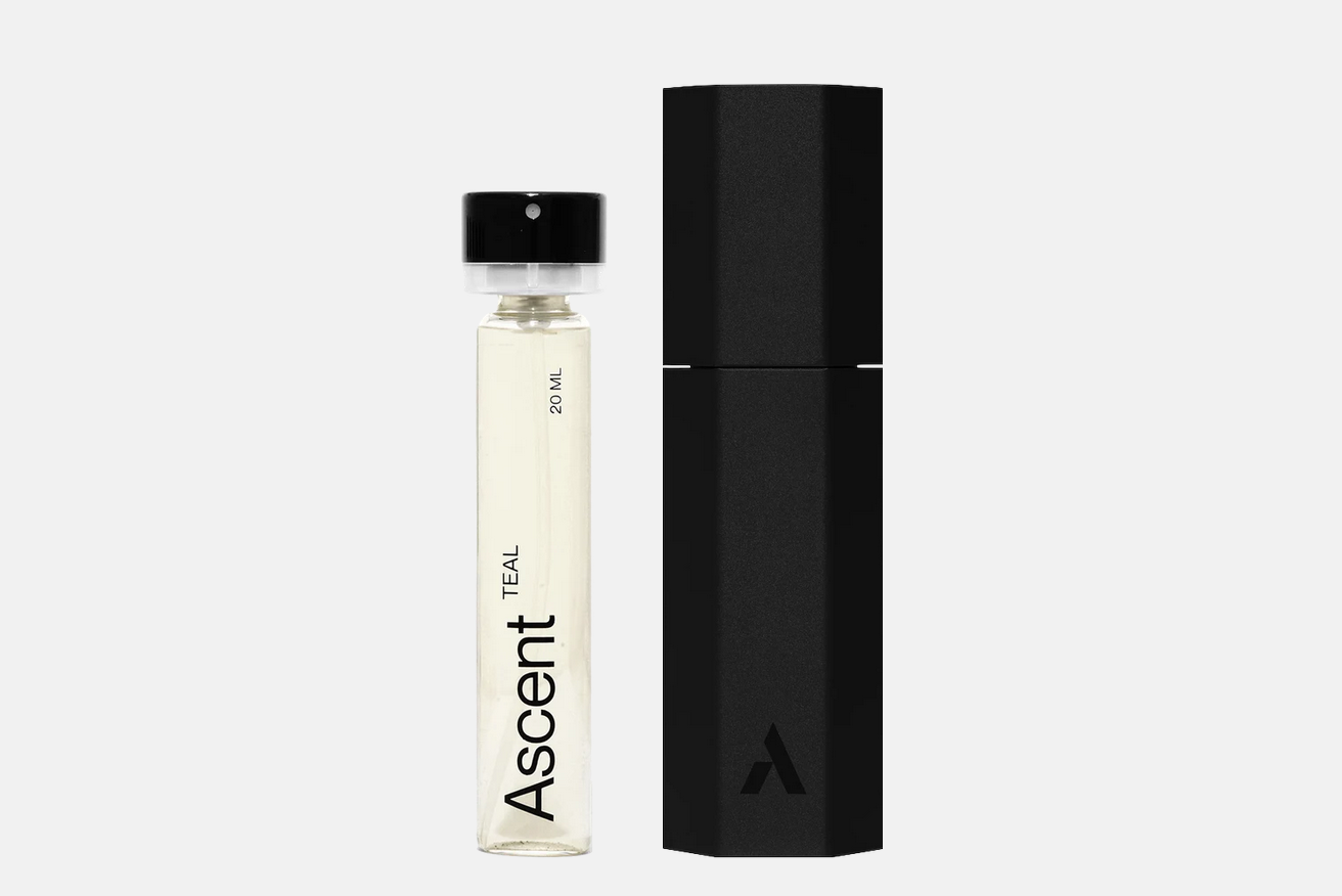 A clear glass teal Ascent Starter Pack - Teal perfume vial labeled “Ascent Teal 20 ml” next to its black hexagonal protective case.