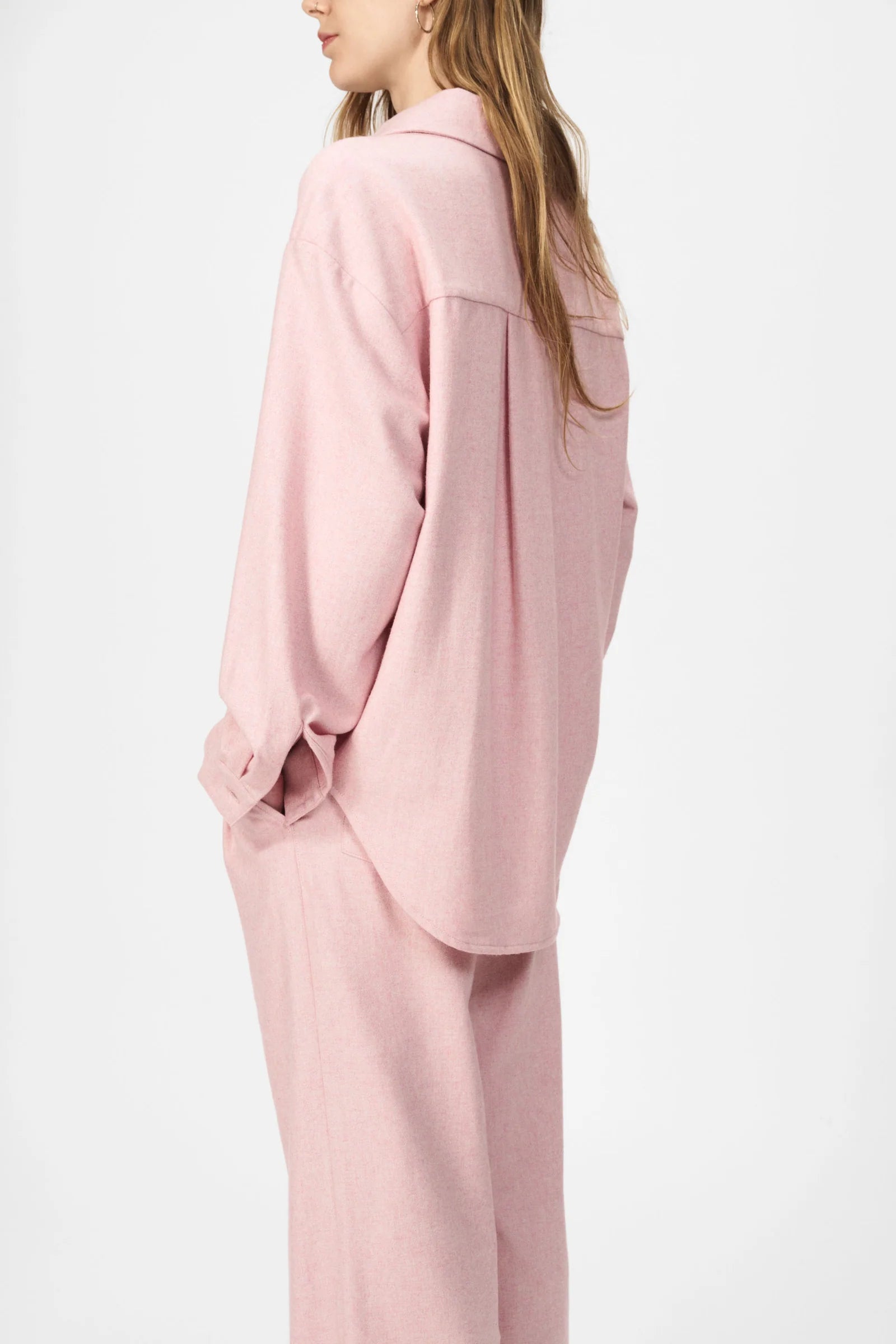 A person is shown from the side and back against a plain background wearing the Nué Notes Bonnyrigg Shirt in blush melange with matching pants.