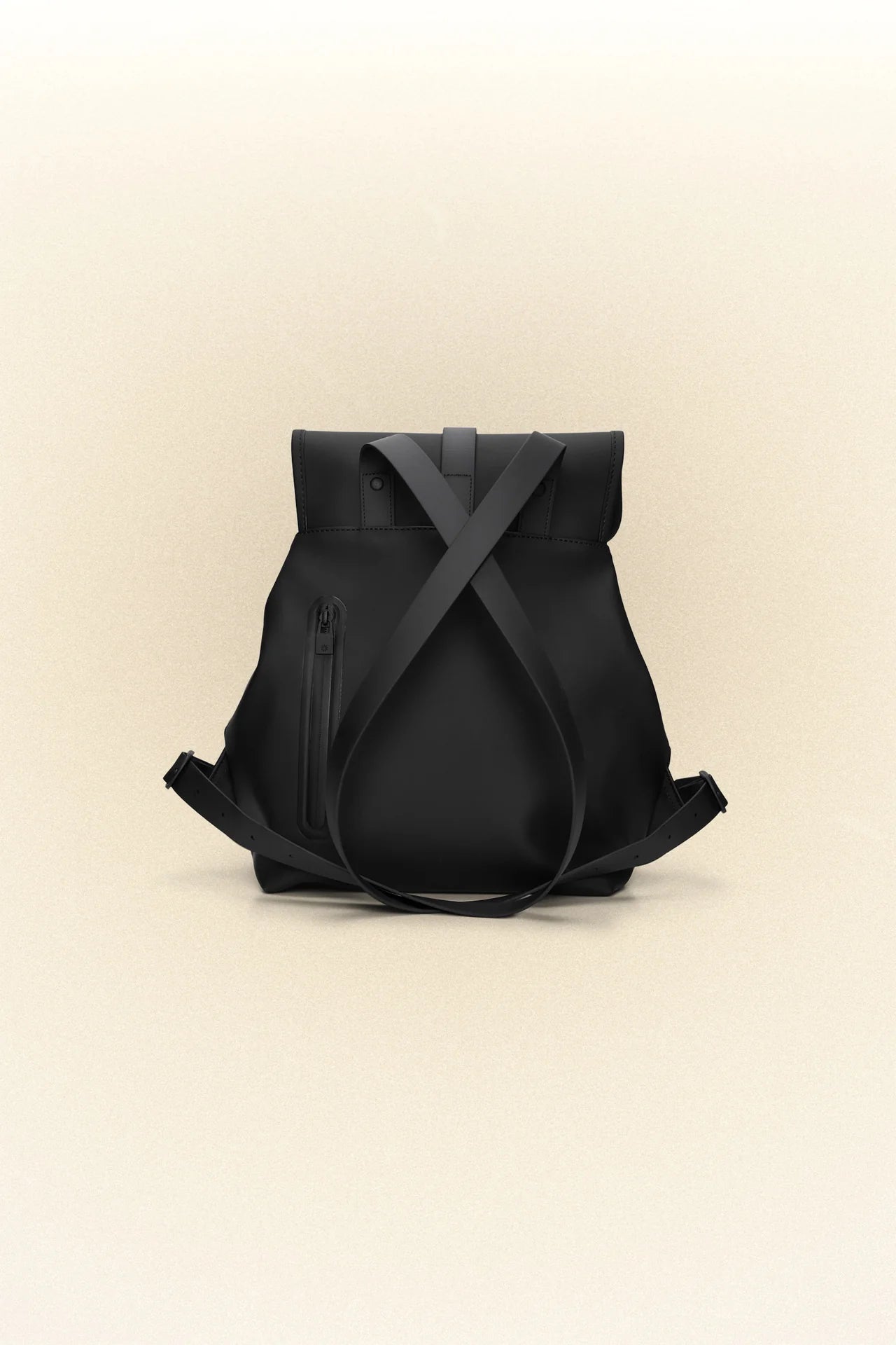 A waterproof black PU coated fabric Bucket Backpack - Black by Rains on a beige background.