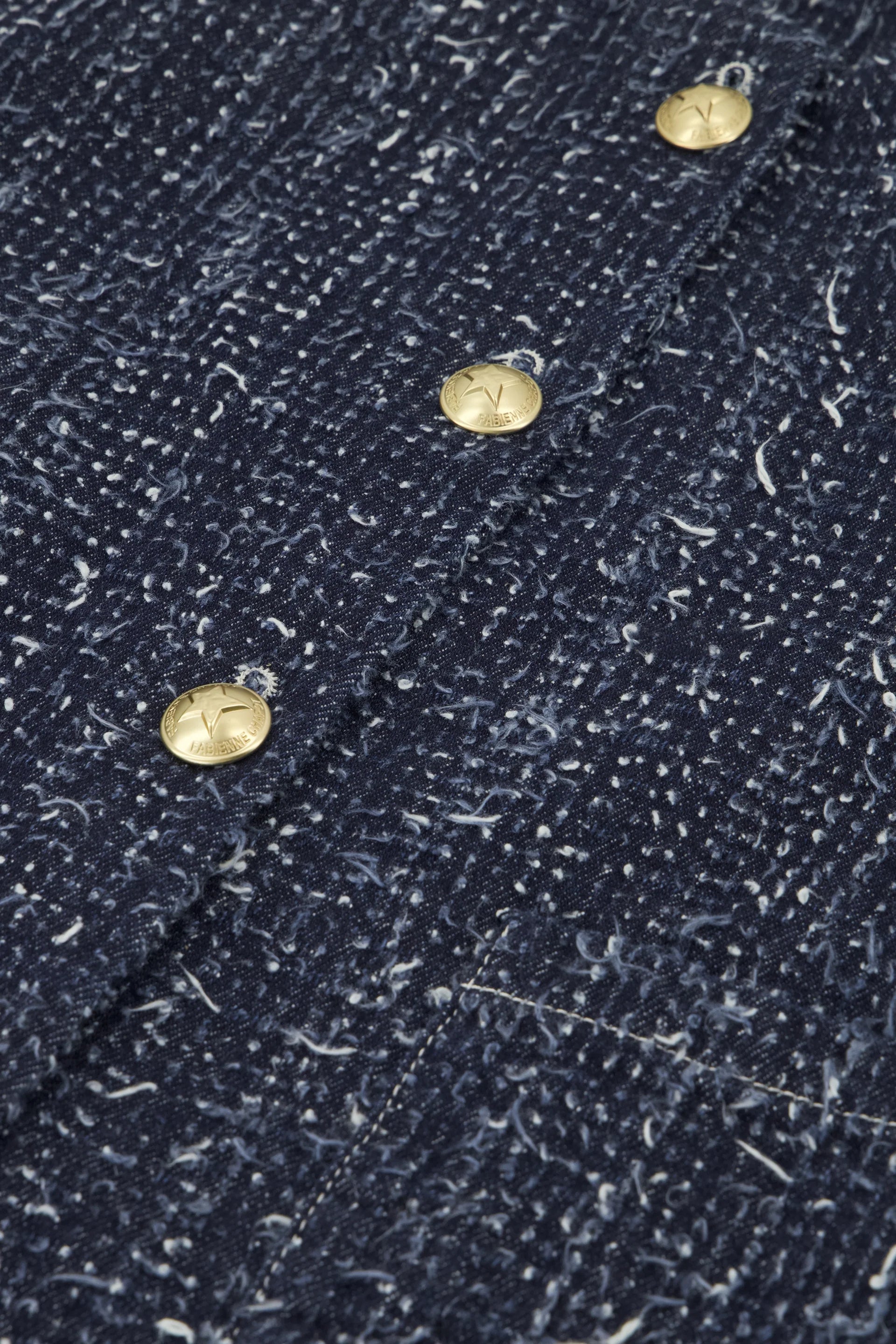 Close-up of the Davis Blazer - Denim by Fabienne Chapot, showcasing its denim-blue color with white speckles and gold star-embossed buttons.