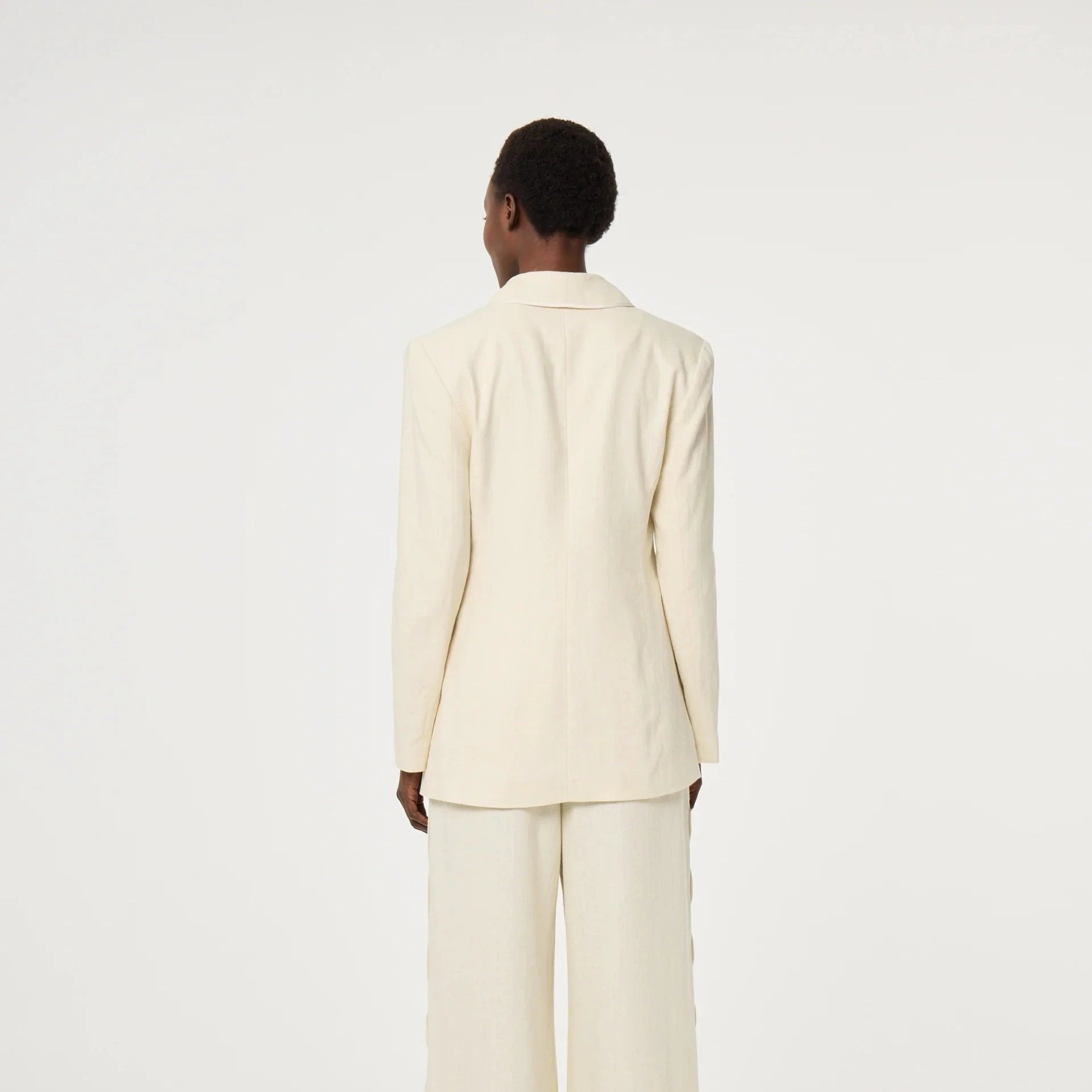 Person wearing a cream-colored suit on a white background