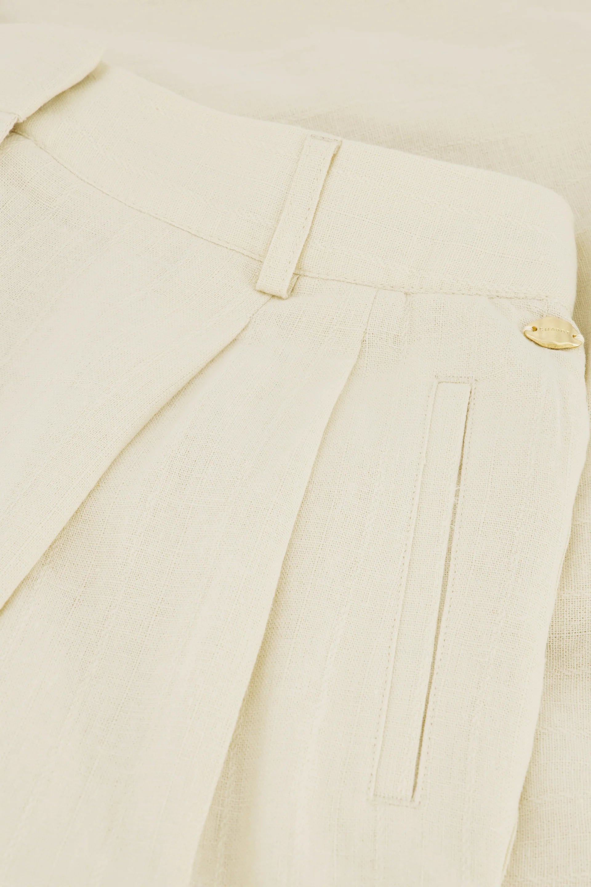 Close-up of Fabienne Chapot's Carlo Shorts in Warm White, featuring belt loop, pleat, welt pocket, and a small gold button on the waistband—ideal for a relaxed summer outfit.
