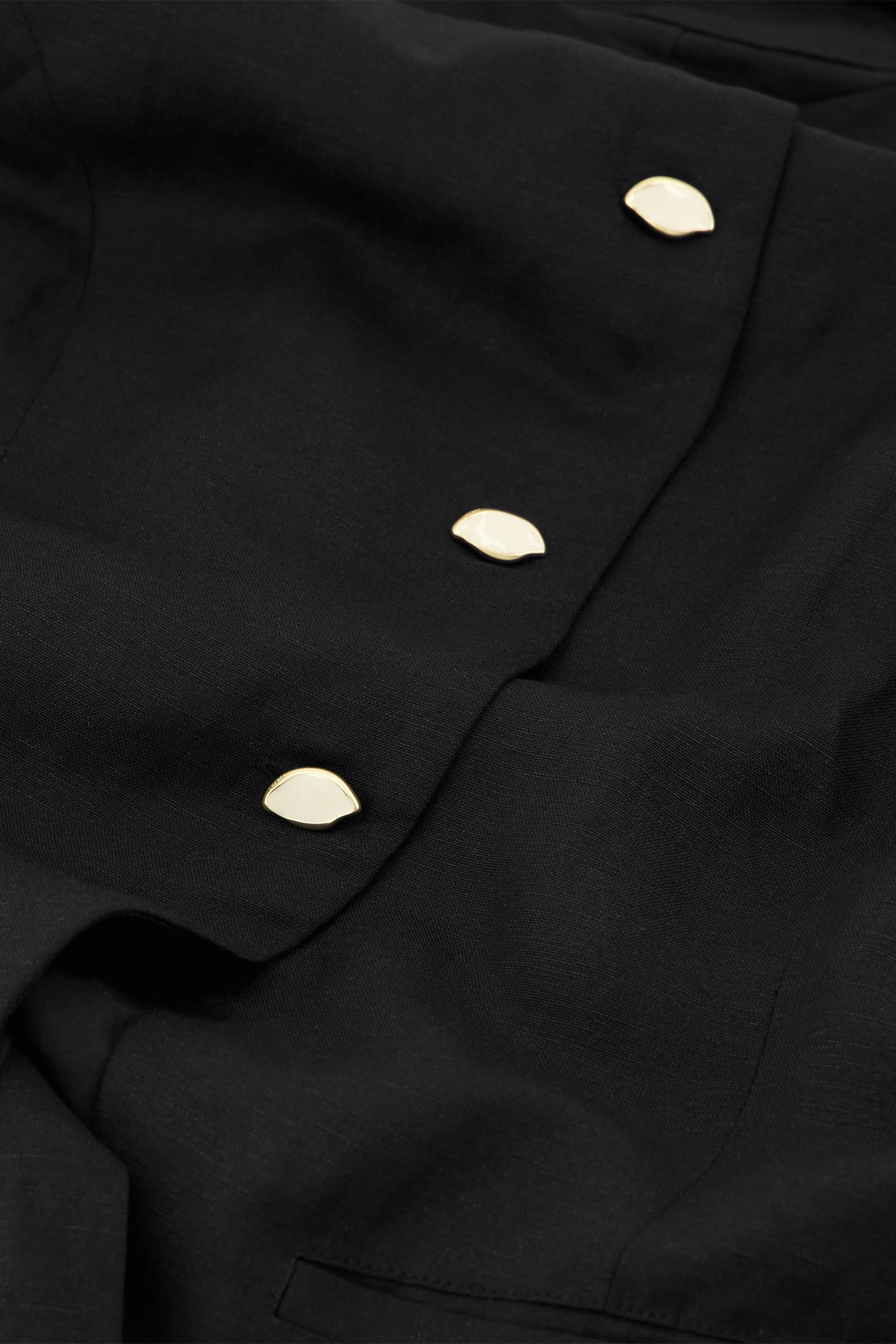 Close-up of a black garment with gold buttons