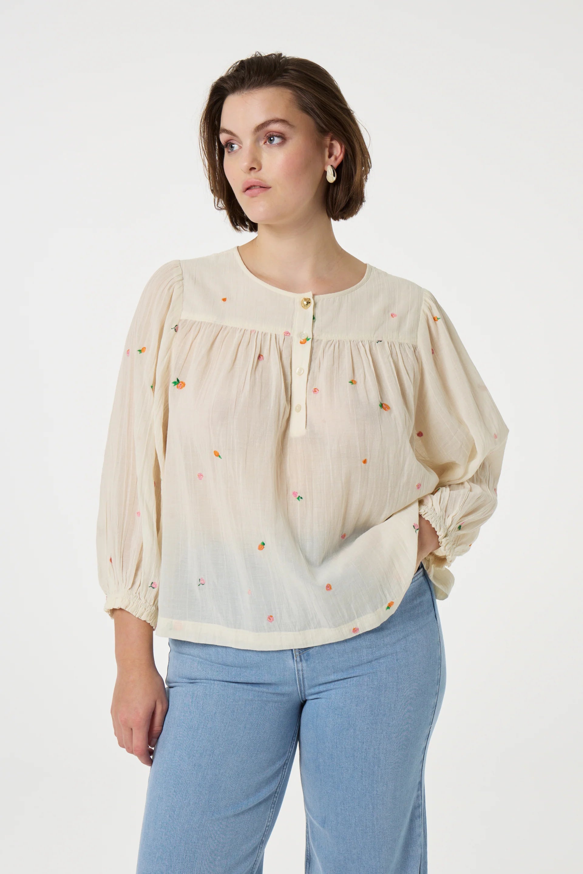 A person wearing the Fabienne Chapot Bindi Top in Cosy White and blue jeans, standing against a plain background.