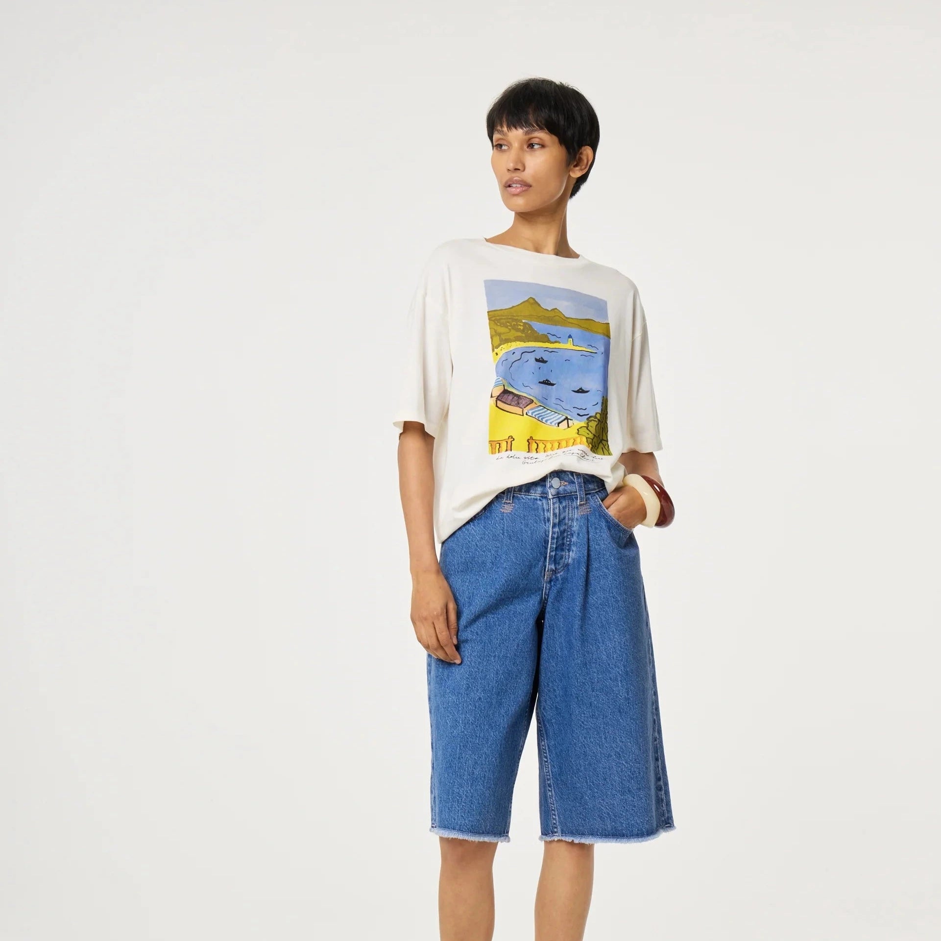 Person wearing a graphic t-shirt and blue jeans on a white background