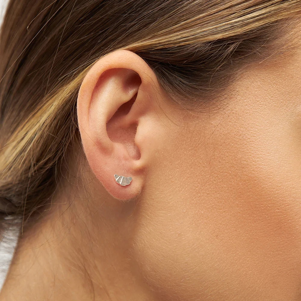 A woman's ear adorned with a sparkling Lulu Copenhagen Croissant Single Stud earring, reminiscent of the elegance found in the French capital.