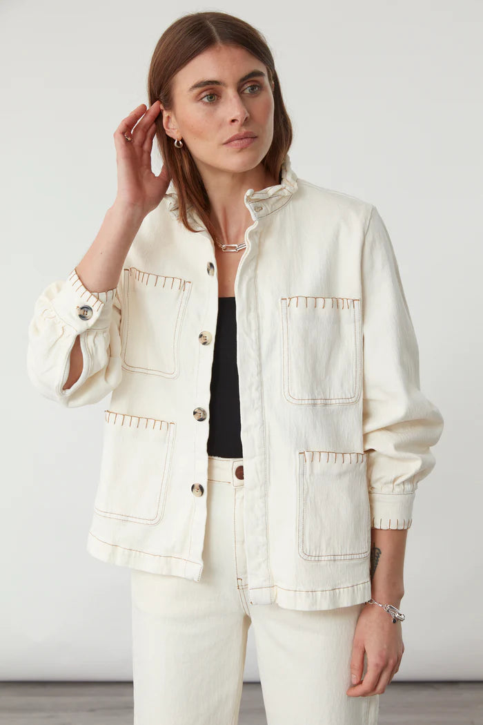 A woman models the Seventy & Mochi Pablo Denim Jacket in ecru, featuring large front pockets, paired with cream pants against a plain light background.