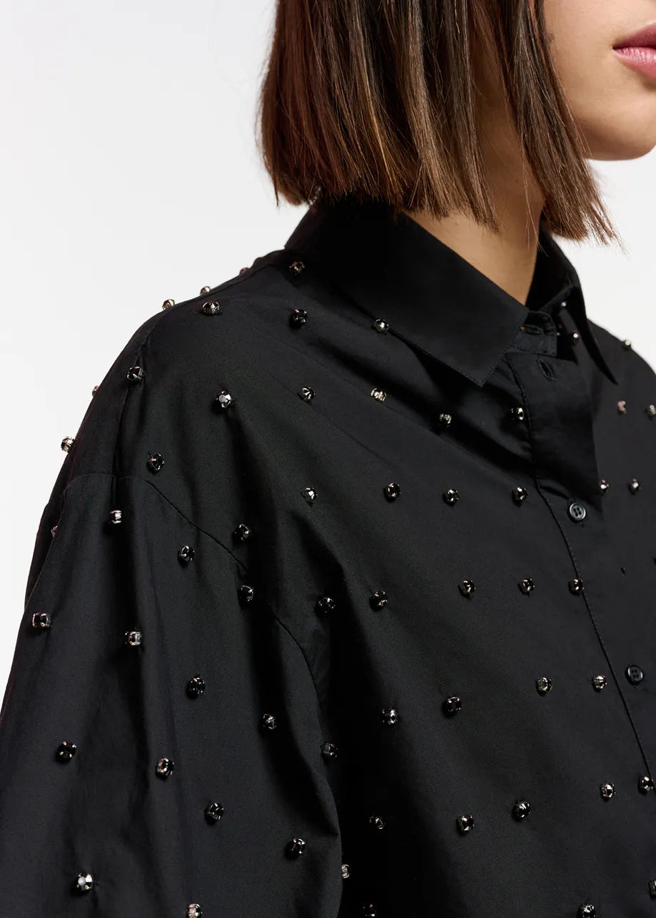 A woman wearing an Essentiel Antwerp East Shirt - Black with studded details.