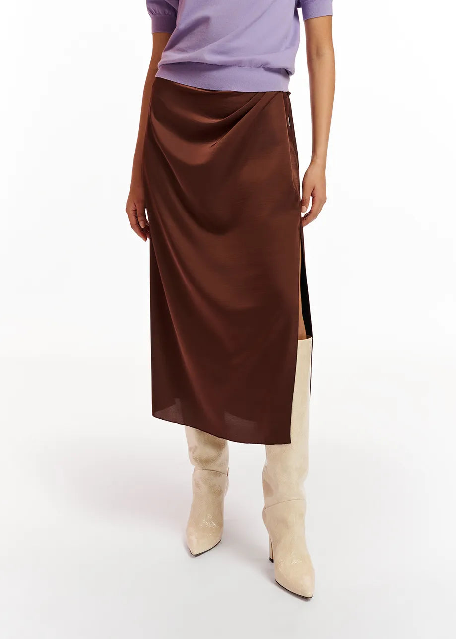 A woman wearing a purple sweater and the Essentiel Antwerp Ellie Skirt - Brown crafted from a recycled polyester-blend fabric.