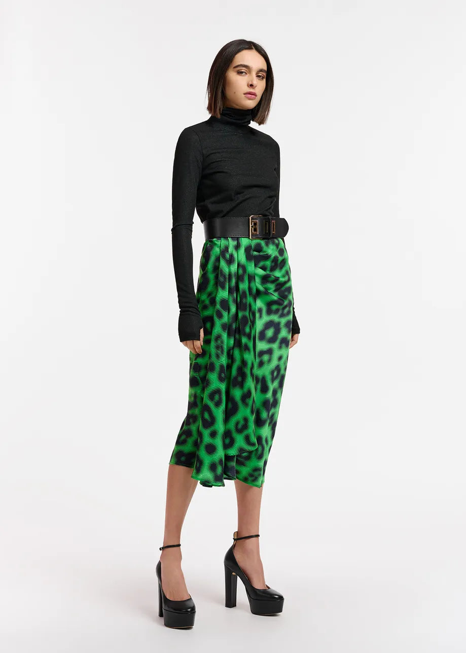 The woman flaunts an Essentiel Antwerp Everest Skirt - Green, in an exquisite wrap-effect style, crafted from a sustainable recycled polyester-blend fabric.