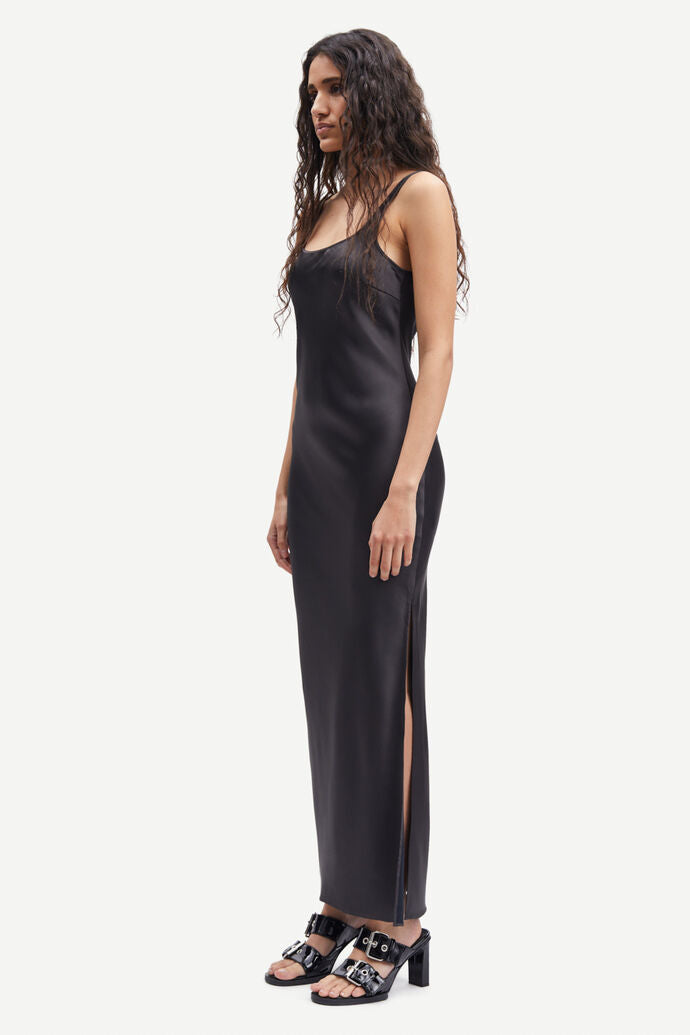The model is wearing a slim fitting black Sunna dress made of recycled polyester by Samsøe Samsøe.