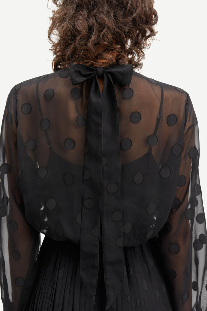 The back view of a woman wearing a Samsøe Samsøe Valentin Dress - Black, with a pleated skirt.