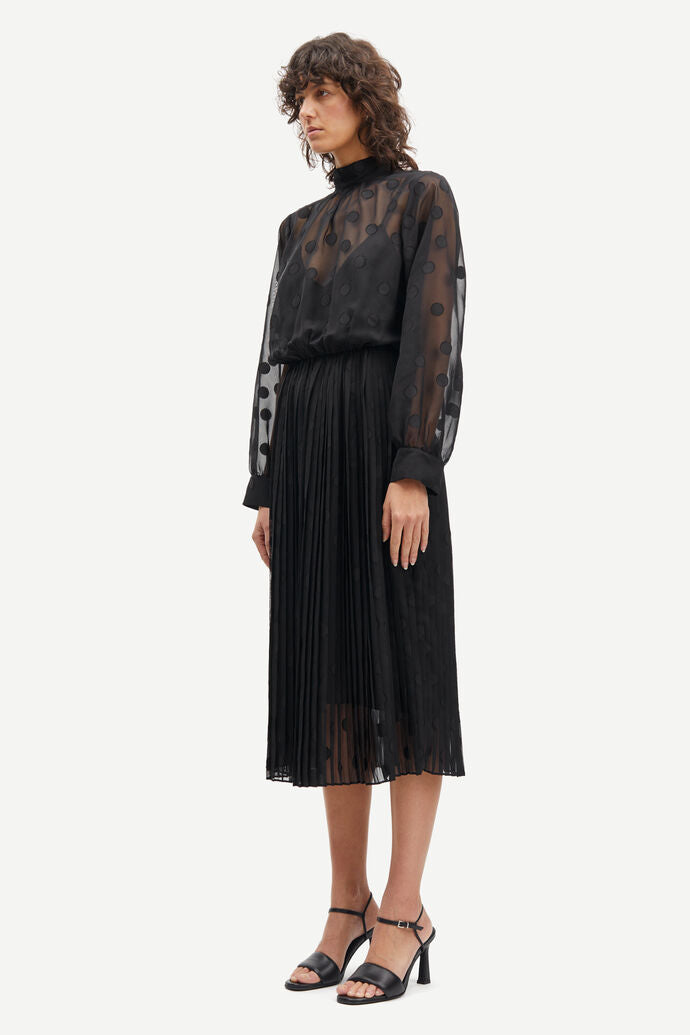 The model is wearing a regular fitting Valentin Dress - Black skirt and Samsøe Samsøe sheer blouse.