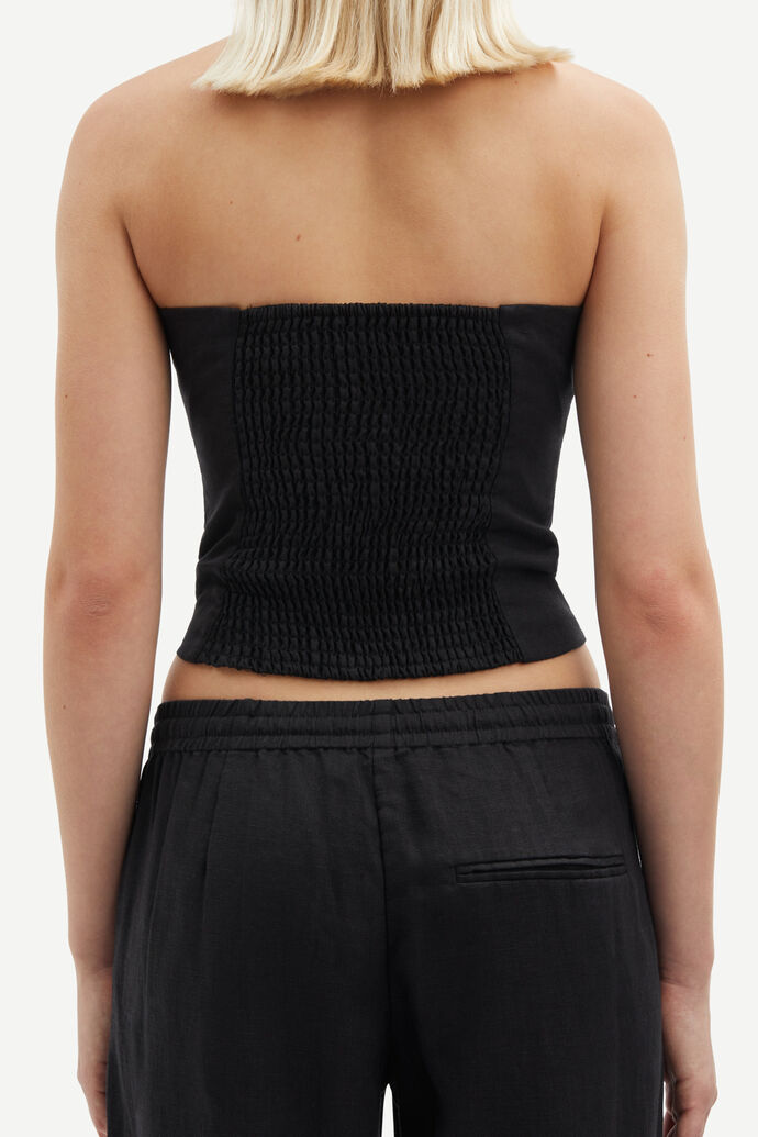 Model wears black bandeau style top in linen - back