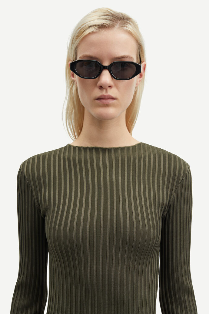 A person wearing the Samsøe Samsøe Sacrane Maxi Dress in Green Rib and black cat-eye sunglasses looks directly at the camera.