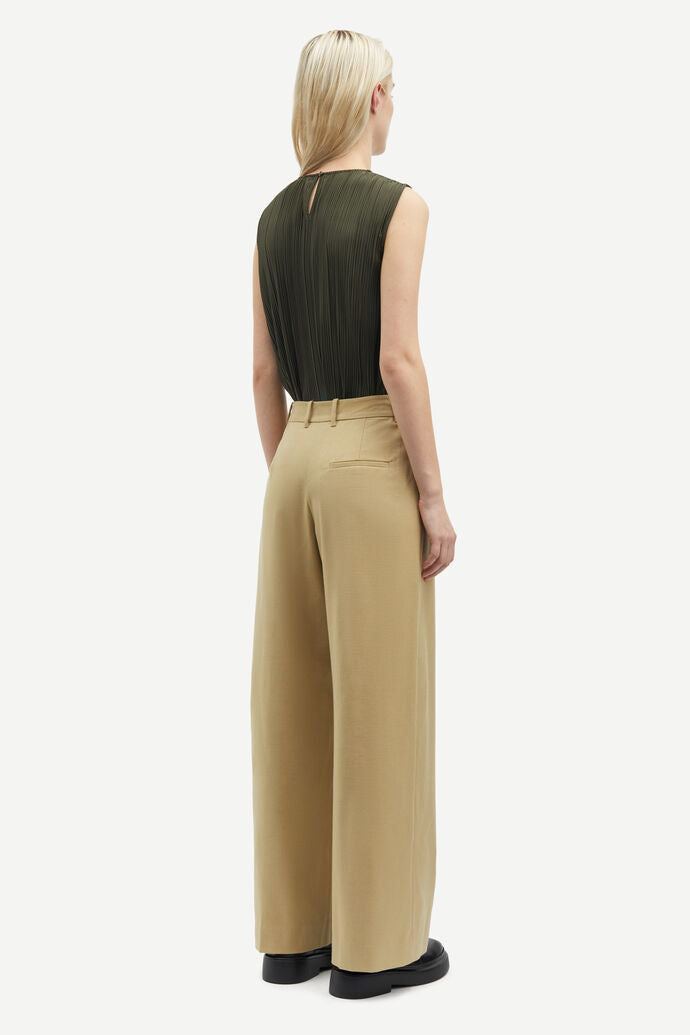 A person with long blonde hair is seen from the back, wearing a sleeveless Sauma O Neck Top in Forest Night by Samsøe Samsøe and beige wide-leg pants.