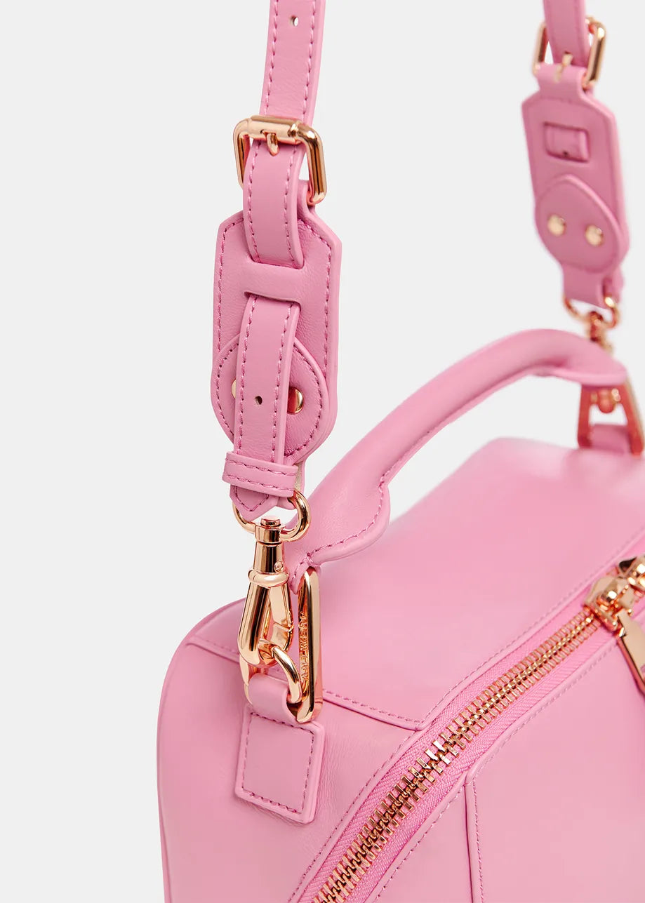 Close-up of the Bobbi Bag - Pink by Essentiel Antwerp, showcasing its luxurious pink leather with a gold zipper, adjustable and detachable strap, and sophisticated gold hardware.