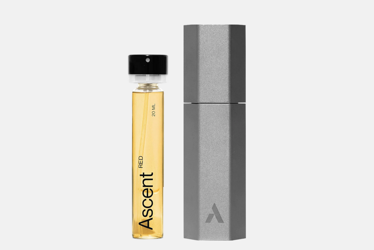 An Ascent Starter Pack - Red 20ml fragrance vial next to a metallic hexagonal carrying case.