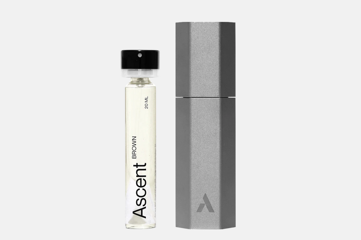 A 20 ml glass Ascent Starter Pack - Brown fragrance vial next to its hexagonal grey protective case.
