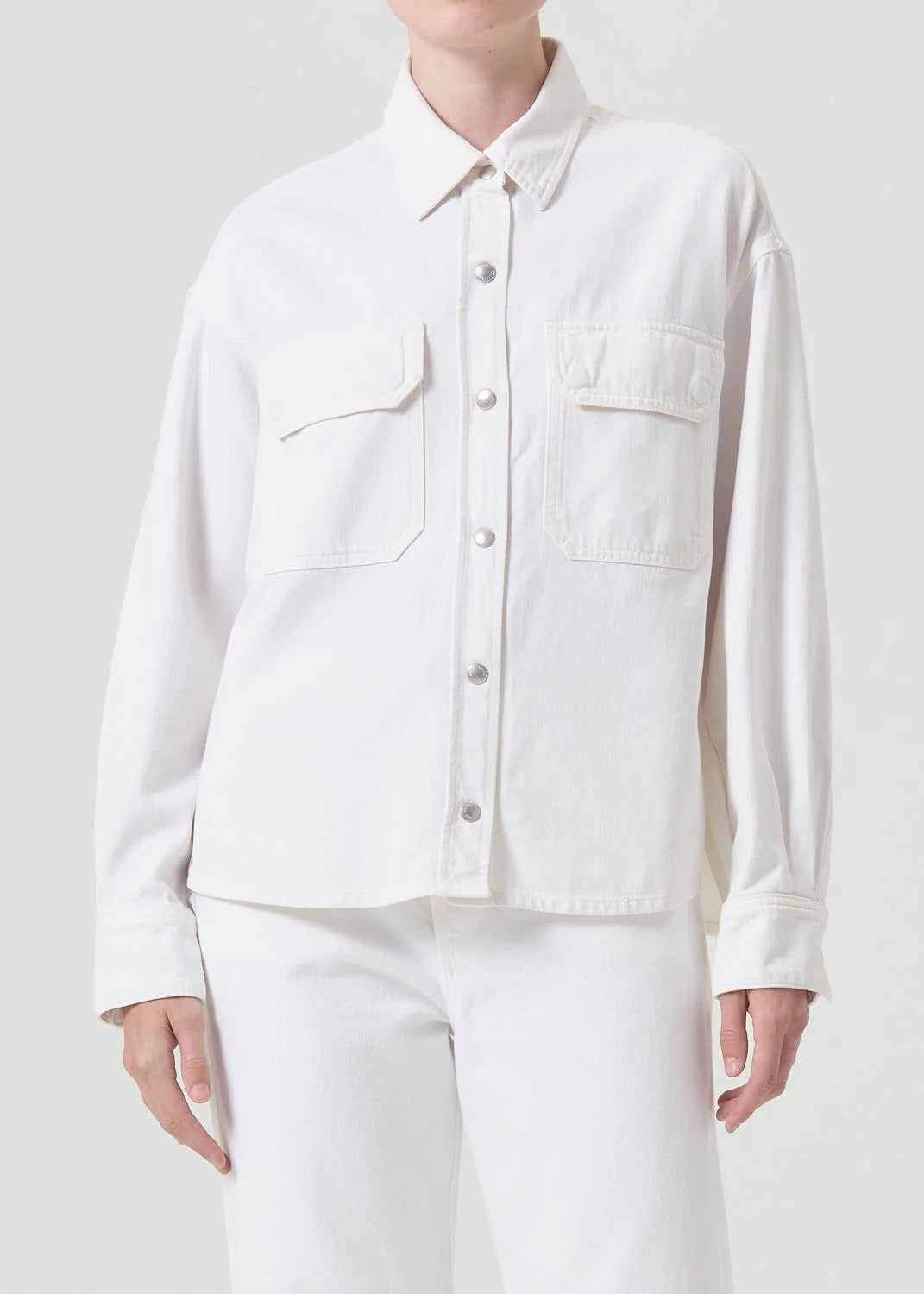 Model wears button down denim shirt in off white wash