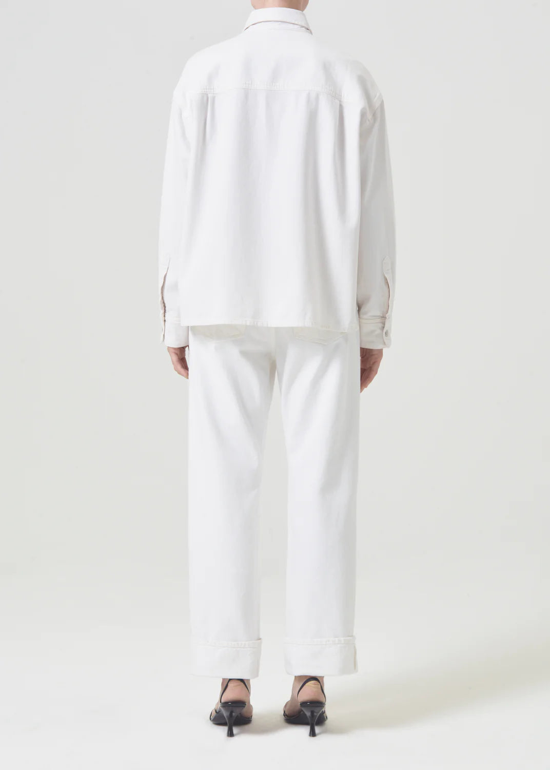 Model wears button down denim shirt in off white wash