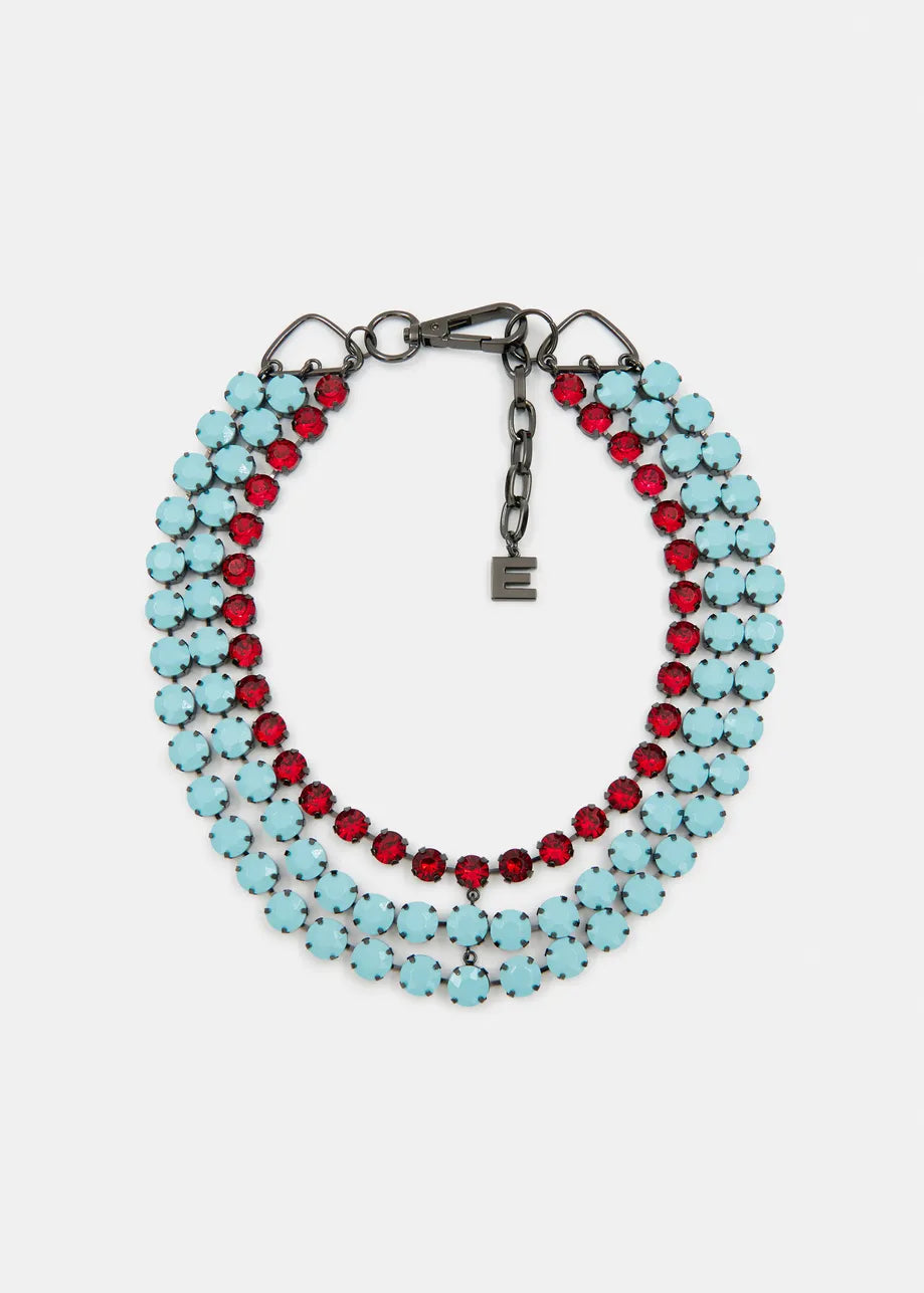 The Layered Rhinestone Necklace by Essentiel Antwerp features three strands: two with light blue stones and one with vibrant red stones. It includes a chain clasp and a small square charm, offering a stunning multicolored rhinestone effect.