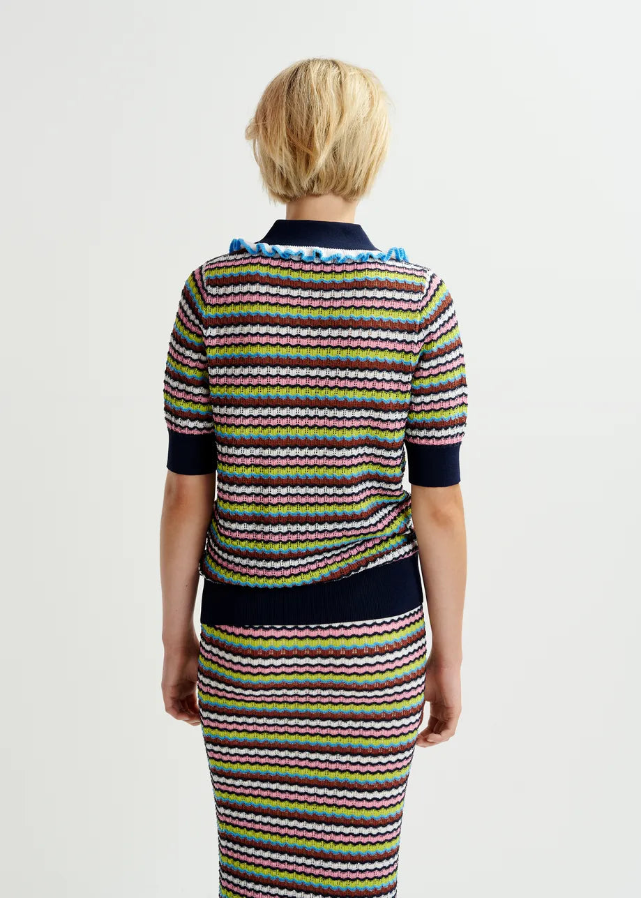 A person with short blond hair is seen from behind, wearing the Essentiel Antwerp Haximum Ruffled Polo - Multi and a matching skirt, posing against a plain white background.