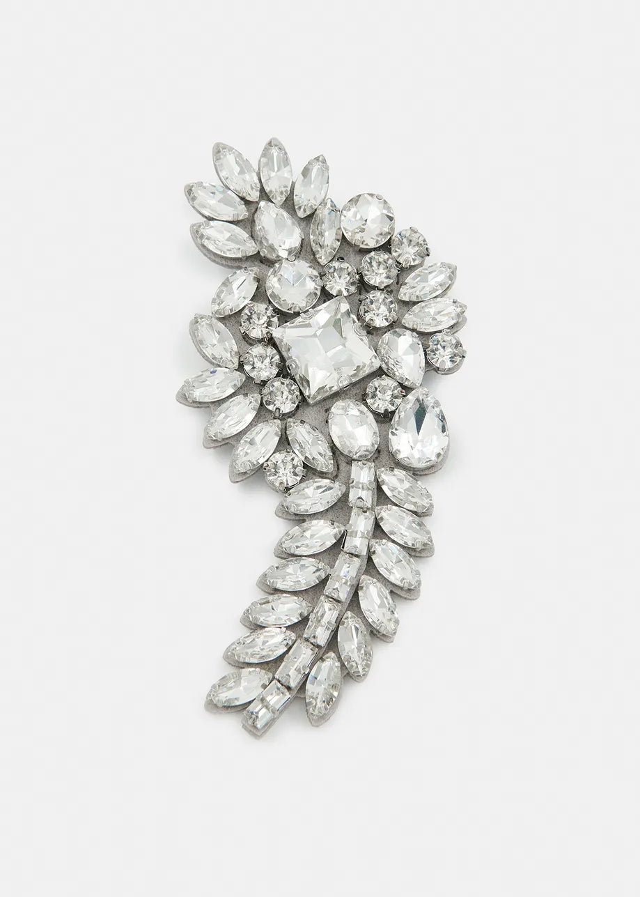 The Rhinestone Brooch - Silver by Essentiel Antwerp showcases a leaf-like design. It features dazzling rhinestones in a cascading pattern on a white background, complemented by elegant silver-tone hardware.