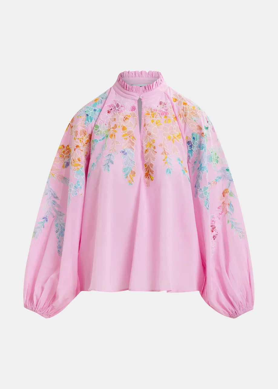 The Hitrus Blouse - Pink by Essentiel Antwerp is a cotton poplin top with floral embroidery on the sleeves and shoulders, featuring a high neck, long balloon sleeves, and a loose fit.