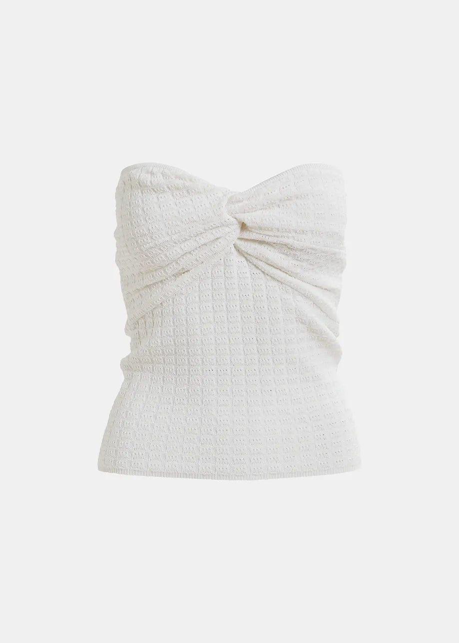 The Holo Knitted Strapless Top in white by Essentiel Antwerp features a textured waffle-knit and front twisted knot, ideal with high-waisted bottoms.