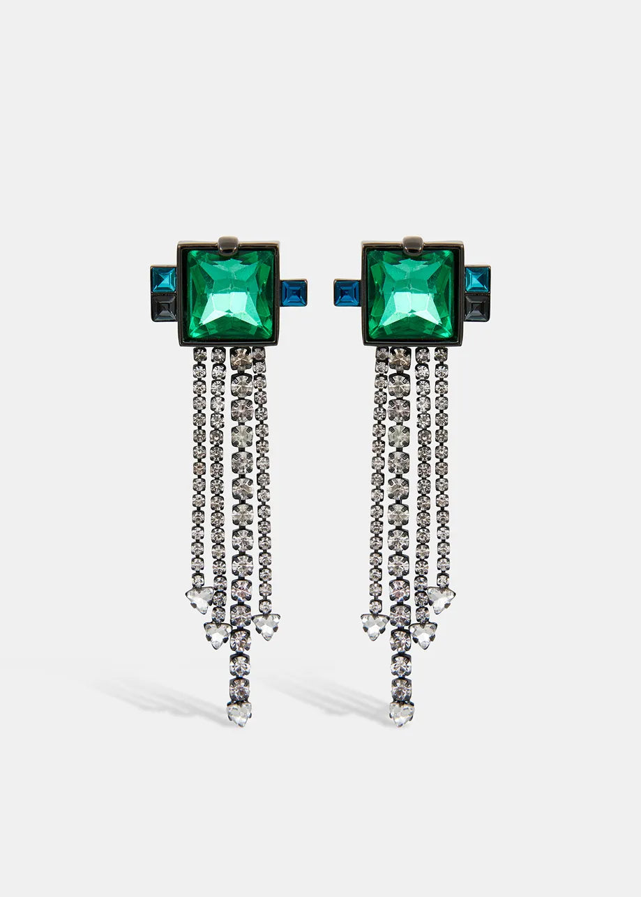 The Rhinestone Earrings by Essentiel Antwerp feature dazzling silver with large green square stones and blue accents, complemented by cascading silver chains that end in small jewels, perfect for an evening look.