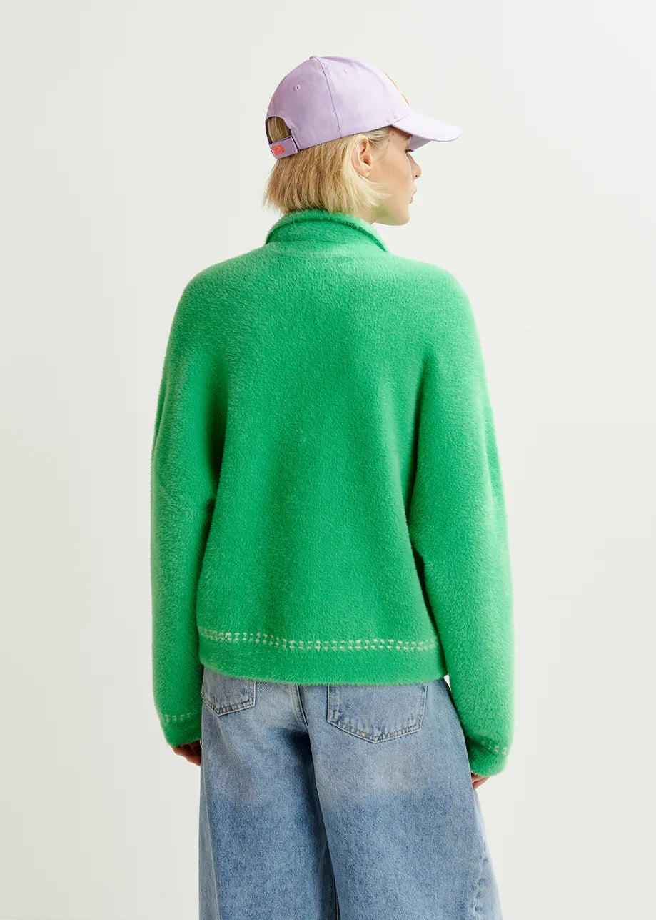 Someone wearing the Hoops Contrast-Knit Cardigan by Essentiel Antwerp in green, paired with a light purple cap and loose blue jeans, stands facing away from the camera against a plain background.