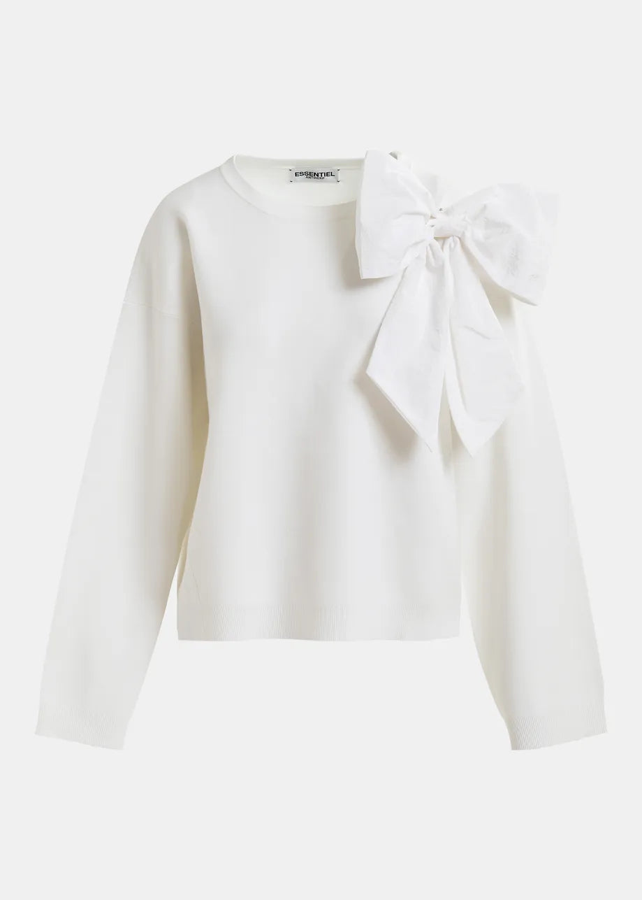 The Hoslo Sweater Removable Bow by Essentiel Antwerp is a white, soft fine-knit, relaxed-fit long-sleeve sweater featuring a large removable bow on the left shoulder, displayed on a plain white background.