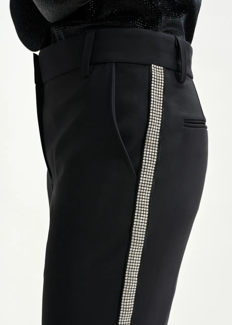Close-up of the Essentiel Antwerp Ibell Flared Rhinestone Trousers in black, made from recycled polyester and accented with vertical rhinestone embellishments along the side seam.