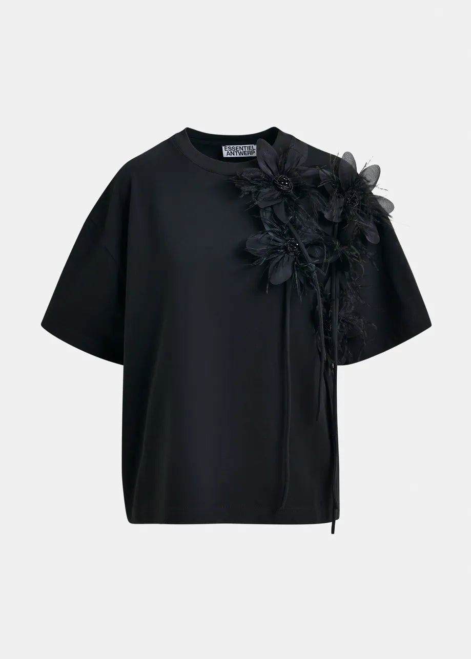 The Ibiscus T-shirt by Essentiel Antwerp is a black, short-sleeve, relaxed-fit tee with a round neck and an oversized floral detail on the left shoulder. Made from 100% cotton for comfort.