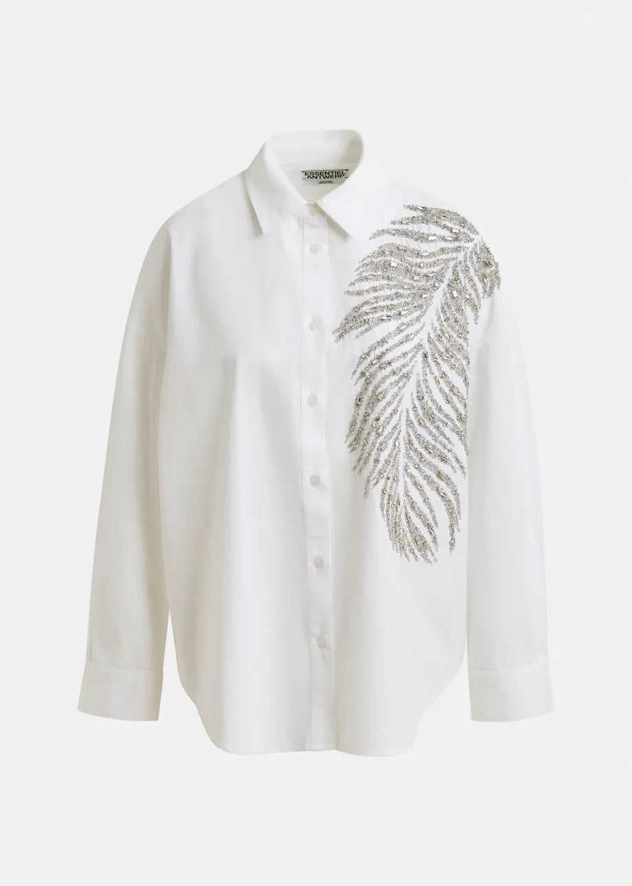 The Iliza Sequin Shirt in white by Essentiel Antwerp is an oversized cotton shirt with long sleeves, detailed with a silver sequin leaf design on the left shoulder and chest for a chic, embellished look.