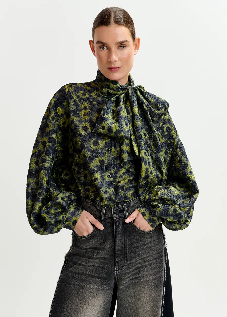 A woman wears the Essentiel Antwerp Illicium Floral Jacquard Shirt in khaki with high-waisted black jeans, standing against a plain light background.